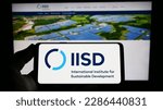 Small photo of Stuttgart, Germany - 04-01-2023: Person holding smartphone with logo of think tank IISD institute on screen in front of website. Focus on phone display. Unmodified photo.