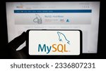 Small photo of Stuttgart, Germany - 07-13-2023: Person holding smartphone with logo of relational database management system MySQL on screen in front of website. Focus on phone display. Unmodified photo.