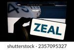 Small photo of Stuttgart, Germany - 08-24-2023: Person holding smartphone with logo of German lottery company ZEAL Network SE on screen in front of website. Focus on phone display. Unmodified photo.