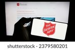 Small photo of Stuttgart, Germany - 10-09-2023: Person holding mobile phone with logo of Protestant charity organization The Salvation Army (TSA) in front of web page. Focus on phone display. Unmodified photo.