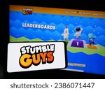 Small photo of Stuttgart, Germany - 11-02-2023: Person holding mobile phone with logo of battle royale multiplayer game Stumble Guys in front of web page. Focus on phone display. Unmodified photo.