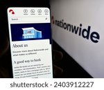 Small photo of Stuttgart, Germany - 12-14-2023: Person holding smartphone with website of British financial institution Nationwide Building Society with logo. Focus on center of phone display. Unmodified photo.