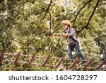 Small photo of Balance beam and rope bridges. Go Ape Adventure. Child concept. Climber child on training. Portrait of a beautiful kid on a rope park among trees. Carefree childhood.