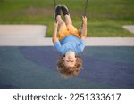 Playground. Kid swinging on swing on playground. Craziness and freedom. Young summer child playing on swing outdoor. Crazy playful child swinging.