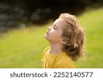 Small photo of Child breathing fresh air. Child faith, praise and happiness and freedom. Kid resting in summer park. Kid put face to the sun, closed her eyes and feeds energy of nature, dreams.