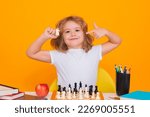 Small photo of Clever concentrated and thinking kid playing chess. Kids brain development and logic game. Kid with chess on yellow isolated studio background.