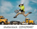 Small photo of Hispanic builder excited jump and run on site construction. Excited builder construction worker in a safety helmet jumping in front of the trucks. Excited crazy builder man in helmet jump outdoor.