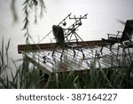 Small photo of Fishing tackle gear two convertible chairs stay outdoor in rain drops falling plop into water on wet wooden pier over natural rainy day background, horizontal picture