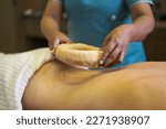Woman having kati vasti Ayurveda treatment in spa while warm oil placing on her back
