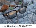 Glasses in black frame placed on a mountain rock surface, representing strength and durability 