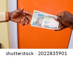 Two african hands receiving or exchanging Nigerian Naira notes, cash or currency