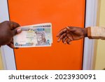 Two african hands receiving or exchanging Nigerian Naira notes, cash or currency