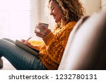 Happy cute lady at home write notes on a diary while drink a cup of tea and rest and relax taking a break. autumn colors and people enjoying home lifestyle writing messages or lists. Blonde curly