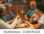 Small photo of Happy family with ufo alien estraterrestrial guest enjoy together hamburgers in fast food. Concept of friendship and diverse people having fun together. Alien explaining at humans