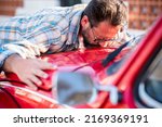 Man kiss his new car. Automobile lovers and owner hugging his vehicle. Concept of dreams and buying. Satisfied guy with closed eyes embracing  the automobile. Dreaming man lying on car kissing it