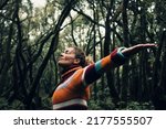 Moody color concept of people and love for nature and planet earth. One person with arms up hugging forest trees around and smiling happy. Environment and woman tourist concept lifestyle