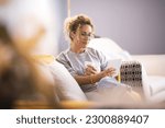 Small photo of Modern lady having relax at home sitting on couch and using ereader tablet to read an online ebook. Woman using technology indoor leisure activity alone enjoying relaxation on couch. Indoor life