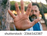 Small photo of One man put his hand in front of the camera to stop. Serious expression. Against climate change and hope for the future. Activist block gesture. War breakout. Nature forest in background environment