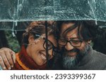Small photo of Romantic couple in love under umbrella in rainy day. Man and woman enjoy relationship and happiness together in winter autumn rain. Romance and people smiling end hugging at the park in leisure moment