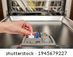 Dishwasher capsule, dishwasher tablets woman puts the capsule in the dishwasher before washing the pasta