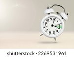 Small photo of Change time. Summer time concept, on a wooden background. A white alarm clock with a minute hand indicates that the time has been moved forward an hour with copy space.