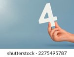 Small photo of number four in hand. Hand holding white number 4 on blue background with copy space. Concept with number four. Birthday 4 years, fourth grade, four day work week