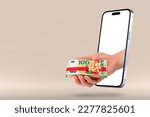 Small photo of Give money online. The hand holds a bundle of money wrapped in a gift ribbon. The hand comes out of a modern mobile phone.
