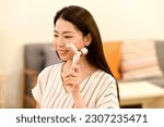 
Young asian woman doing skin care with facial roller