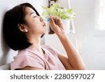 Small photo of Asian woman feeling dizzy and faint hand holding nasal inhaler and breathing deep menthol to get refresh