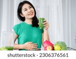 Small photo of Asian woman experiencing delight and vitality relishes a refreshing blend of green fruits and vegetable juice, embracing its benefits for healthy digestive system, nutrient-rich fiber detoxification
