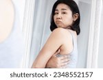 Small photo of Asian woman unhappy with back bra bulge fat , checking upper back fat in a mirror