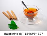 Small photo of A cup of tea, Cinnamon tea, Cinnamon drink with cinnamon stick on a Tea Bag, leaf on a white background, Spoon, Transparent cup, Ceylon Tea, Sri lanka, Ceylon Cinnamon