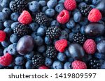Background of fresh fruits and berries. Ripe blackberries, blueberries, plums, raspberries. Mix berries and fruits. Top view. Background berries and fruits. Black-blue and red food.