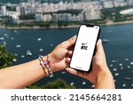 Small photo of Girl holding smartphone with Nike Training Club NTC app on screen. City and bay with some boats in the background. Rio de Janeiro, RJ, Brazil. March 2022.