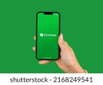 Small photo of Female hand holding a smartphone iPhone with Evernote for note taking, organizing, and archiving app on the screen. Green background. Rio de Janeiro, RJ, Brazil. June 2022.