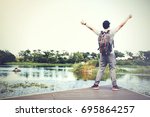 Back of happy and winning travel backpacker raising hands in countryside nature scene 