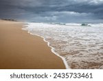 Small photo of wave rolling onto sand at wooli beach on overcast day in nsw australia
