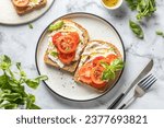 Small photo of Sandwiches or toasts with tomatoes, cream cheese, olive oil and basil on a plate on white marble background. Traditional italian mediterranean food. Horizontal, top view, flat lay