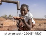 Small photo of Close-up of an African girl collecting water from a village tap in an arid equatorial area; climate change concept
