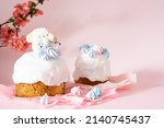 Easter cake with white icing and blue meringues Easter decorative lamb on a pink background with spring cherry blossoms and copy space. Easter Ukraine orthodox sweet bread. Easter card concept.
