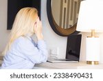 Tired european blonde business woman working on a laptop in her home office Covering her face with her hands and crying. The concept of negative remote work, freelancer no luck.
