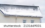 Small photo of Metal Downpipe system, Guttering System, External downpipes and drainage pipes under snow. Corner of house with roof made of gray metal tiles and gutter covered with thick layer of snow in winter.