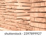 Wooden planks at lumber warehouse. Image toned in trendy Peach Fuzz pantone color of Year 2024. Piles of wooden boards at store outdoors. Wood timber stack of wooden planks construction material.