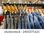 Small photo of Jeans on the hanger in the store. Clothes on hangers in shop for sale. Blur background. Fashionable clothes in a boutique. Various clothing on market. Shopping in store.