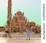 Small photo of young girl on the background of the El Mustafa Mosque in the Old City of Egypt. Travel to egypt concept. An ancient mosque in the tourist city of Sharm El Sheikh. High quality photo