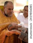 Small photo of Ukraine, Khmelnitsky 02.10.2022. Infant baptism. Water is poured on the head of an infant. Christening the baby at the Orthodox church. Christian rite. orthodox rite. Christian baptism of a child