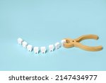 Small photo of Tooth extraction with a dental instrument with forceps. A model of teeth in the shape of a smile. Problems with wisdom teeth, toothache