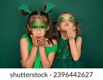 Small photo of Beautiful girls with makeup in the guise of a green dragon are blowing kisses while waiting for the new year
