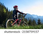 Small photo of Woman cyclist with a mountain bike in a hills landscape. Visible logos and names was retouched or changed beyond recognition.