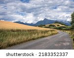 a dirt road next to a grain field heading into the high mountains. Kriváň in the High Tatras stands out in the background.